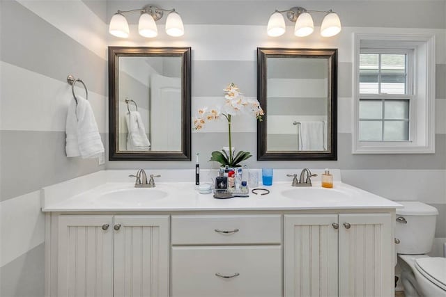 full bathroom featuring a sink, toilet, and double vanity