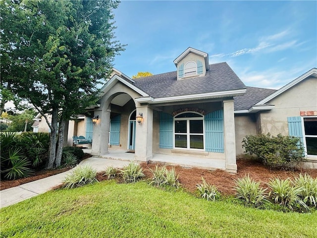 114 Wedge Wood Ct, Brunswick, GA 31525 - view of front facade with roof with shingles, a front yard, stucco siding, and covered porch