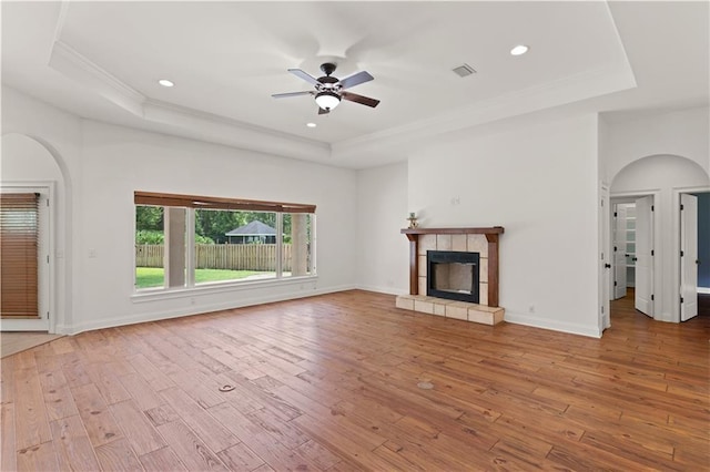 114 Wedge Wood Ct, Brunswick, GA 31525 - unfurnished living room with a raised ceiling, wood-type flooring, a ceiling fan, arched walkways, and a tile fireplace