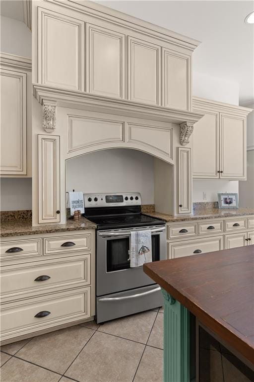 114 Wedge Wood Ct, Brunswick, GA 31525 - kitchen with stainless steel electric range, light tile patterned flooring, cream cabinets, and dark stone counters
