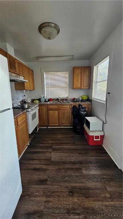 2645 Oriole St, Brunswick, GA 31520 - kitchen with brown cabinetry, white appliances, and under cabinet range hood