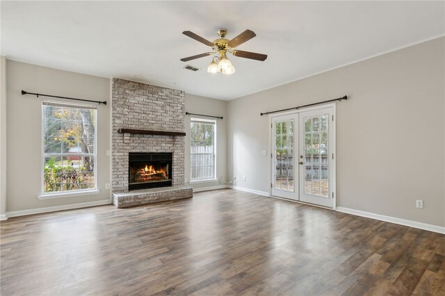 unfurnished living room featuring ceiling fan, french doors, dark wood-type flooring, and a brick fireplace