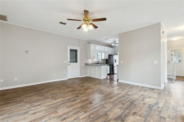 unfurnished living room featuring ceiling fan, sink, and wood-type flooring