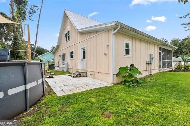 rear view of house featuring a sunroom, a yard, cooling unit, a pool, and a patio area