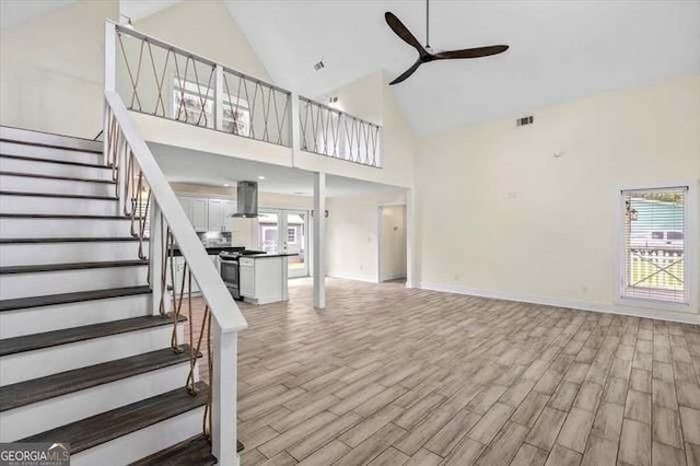 unfurnished living room featuring ceiling fan, plenty of natural light, and high vaulted ceiling