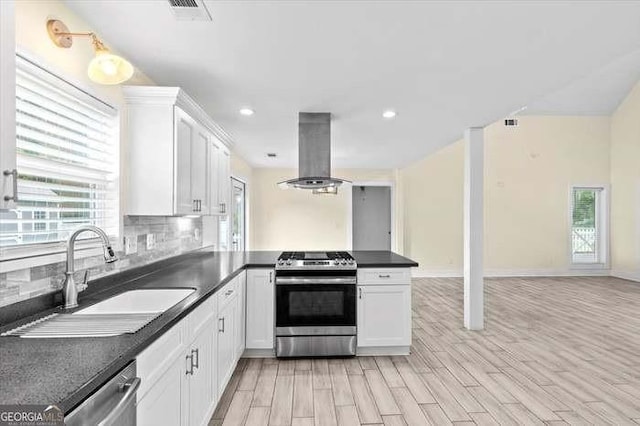 kitchen with island exhaust hood, backsplash, stainless steel appliances, sink, and white cabinetry