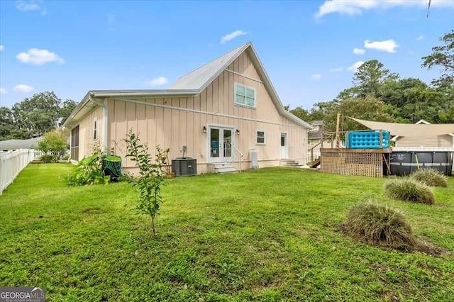 rear view of house featuring french doors, a yard, and central AC unit