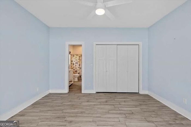 unfurnished bedroom featuring ceiling fan, light hardwood / wood-style floors, a closet, and ensuite bath