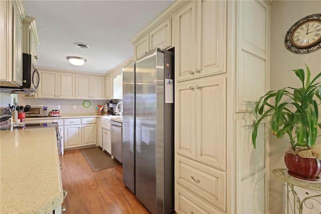 314 King David Rd, Jesup, GA 31545 - kitchen featuring stainless steel appliances, cream cabinets, light wood-type flooring, and a textured ceiling