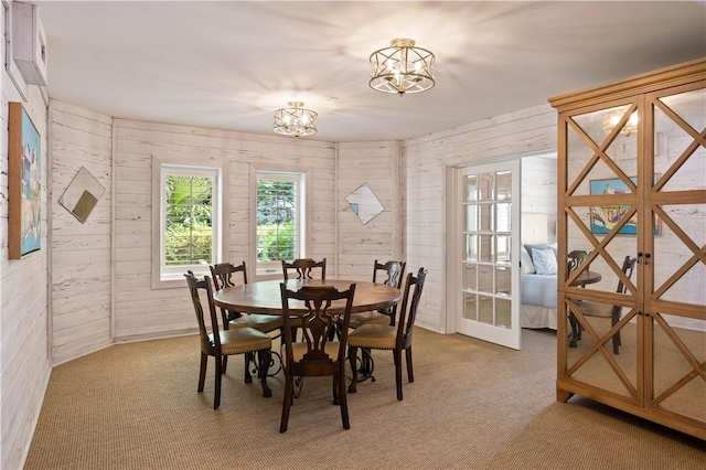 dining space with light colored carpet, wooden walls, and a chandelier