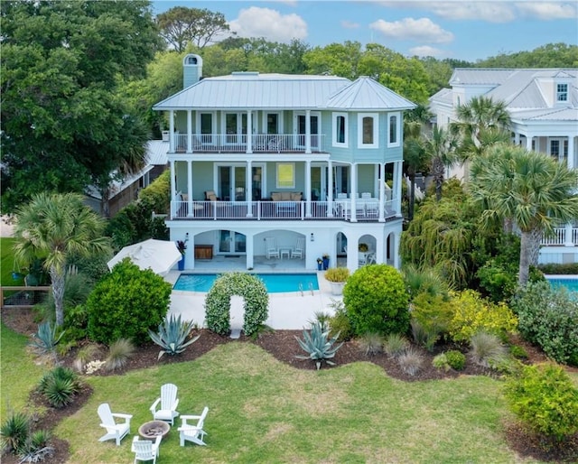 back of house featuring a lawn, a patio area, and a balcony