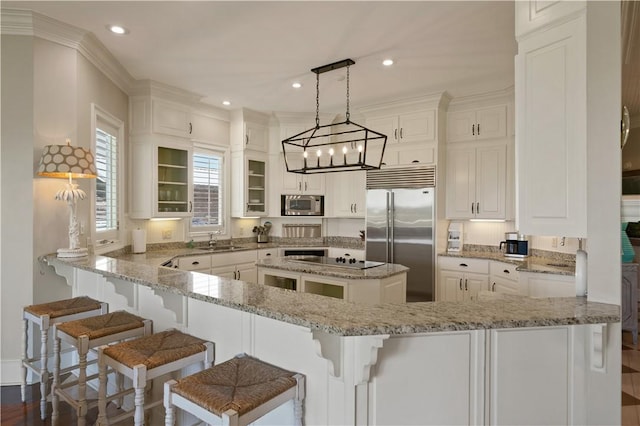 kitchen featuring dark hardwood / wood-style flooring, light stone counters, sink, built in appliances, and white cabinetry