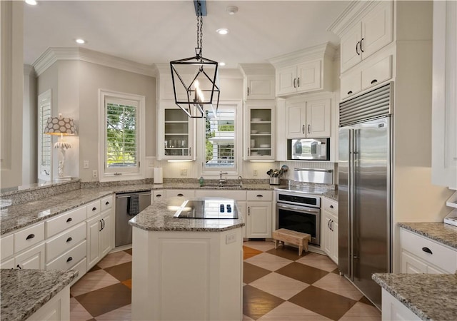 kitchen with crown molding, built in appliances, white cabinets, a kitchen island, and hanging light fixtures