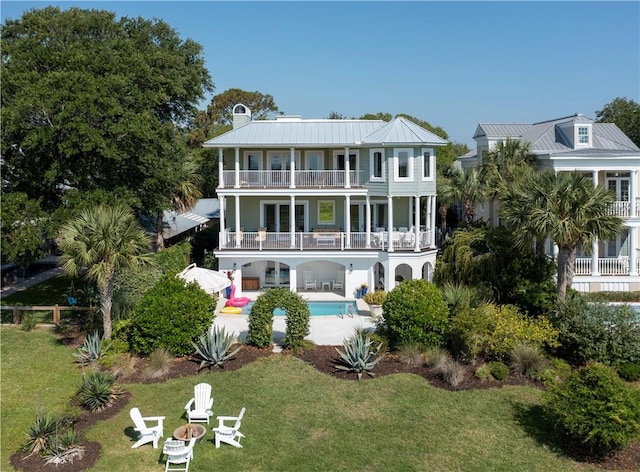 rear view of property featuring a patio area, a balcony, and a yard