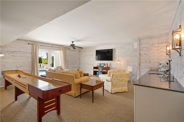 living room with wooden walls, ceiling fan, and light carpet