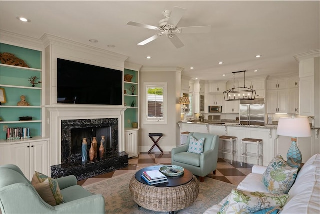 living room featuring built in features, ceiling fan, ornamental molding, and a premium fireplace