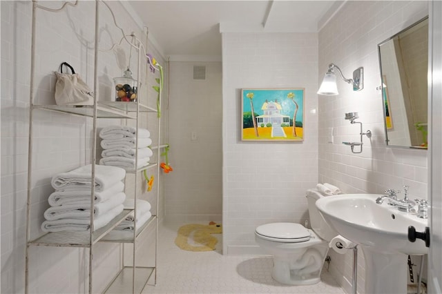 bathroom featuring tile patterned flooring, toilet, and tile walls