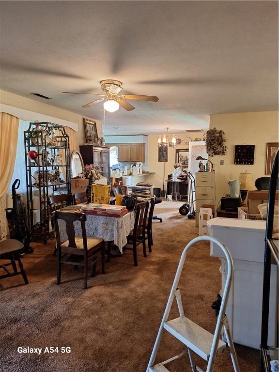 dining room featuring visible vents, dark carpet, and ceiling fan with notable chandelier