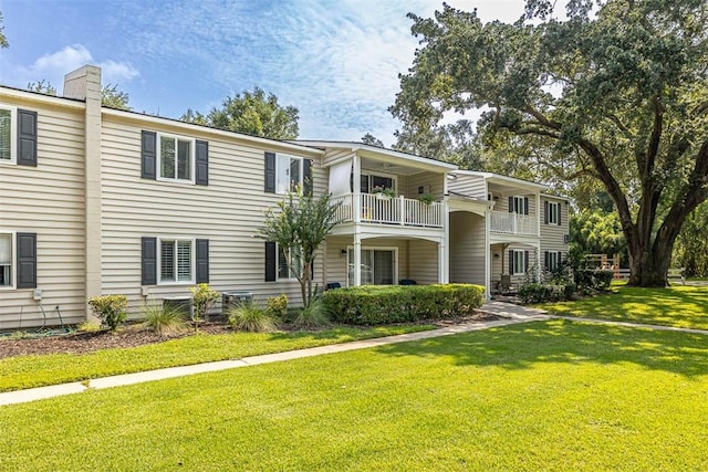 view of front of property featuring a balcony and a front yard