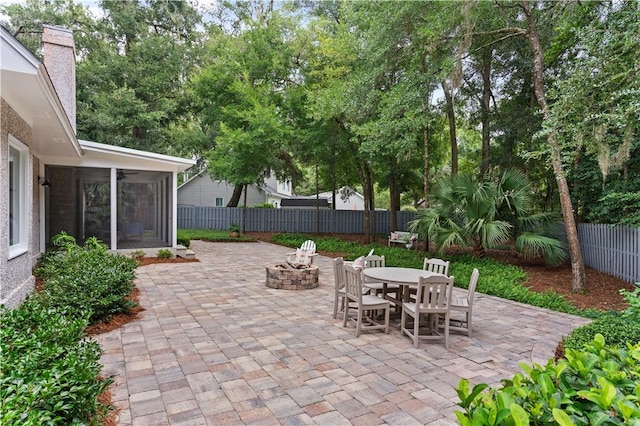 view of patio featuring an outdoor fire pit, outdoor dining area, a fenced backyard, a sunroom, and a ceiling fan