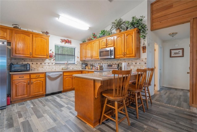 4068 3r Fish Camp Rd, White Oak, GA 31568 - kitchen with appliances with stainless steel finishes, a sink, a breakfast bar area, wood finished floors, and lofted ceiling