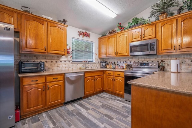 4068 3r Fish Camp Rd, White Oak, GA 31568 - kitchen with stainless steel appliances, a sink, a textured ceiling, brown cabinets, and vaulted ceiling