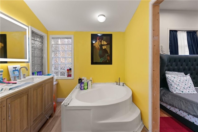 bathroom featuring a bathing tub, vanity, vaulted ceiling, and hardwood / wood-style flooring