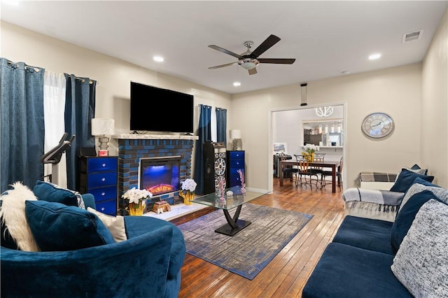 living room with a fireplace, wood-type flooring, and ceiling fan