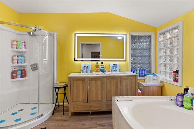 bathroom featuring shower with separate bathtub, vanity, vaulted ceiling, and wood-type flooring