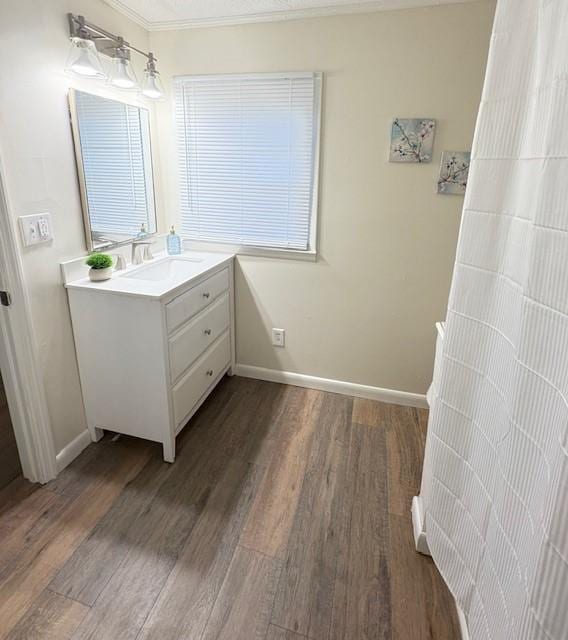 bathroom with vanity, baseboards, ornamental molding, and wood finished floors