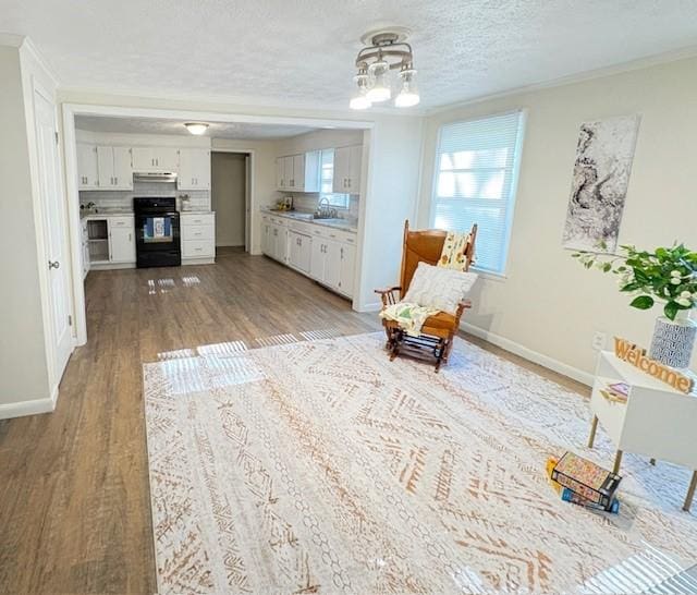 living area with crown molding, baseboards, a chandelier, and wood finished floors