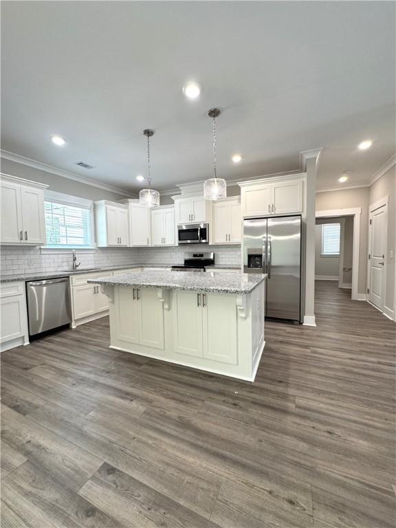 193 W Melody Dr, Jesup, GA 31545 - kitchen with stainless steel appliances, ornamental molding, a kitchen island, white cabinets, and plenty of natural light