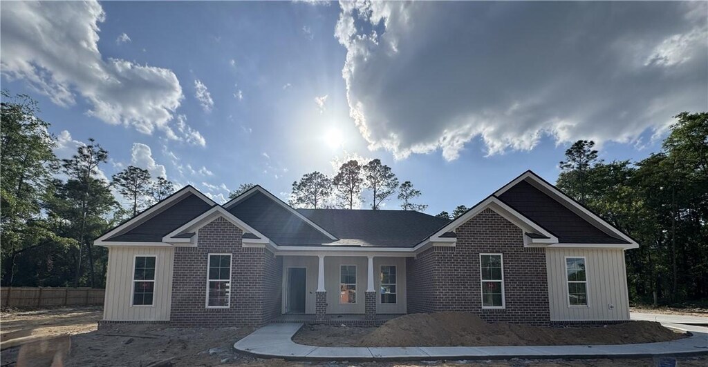 view of front of property with covered porch, brick siding, and fence