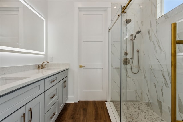 bathroom with vanity, a tile shower, and wood-type flooring