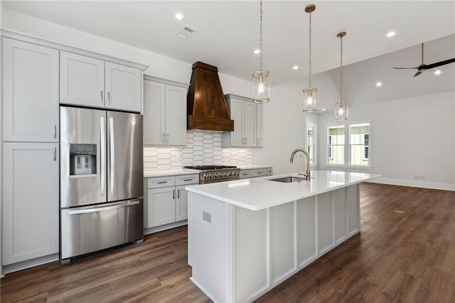 kitchen with sink, premium range hood, pendant lighting, a kitchen island with sink, and appliances with stainless steel finishes