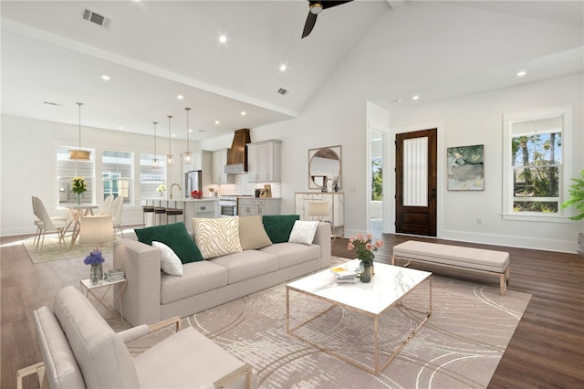 living room featuring hardwood / wood-style flooring, ceiling fan, sink, and high vaulted ceiling