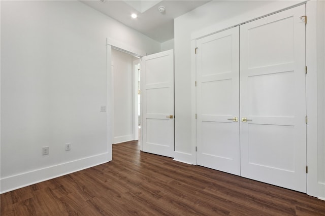 unfurnished bedroom with a closet and dark hardwood / wood-style floors