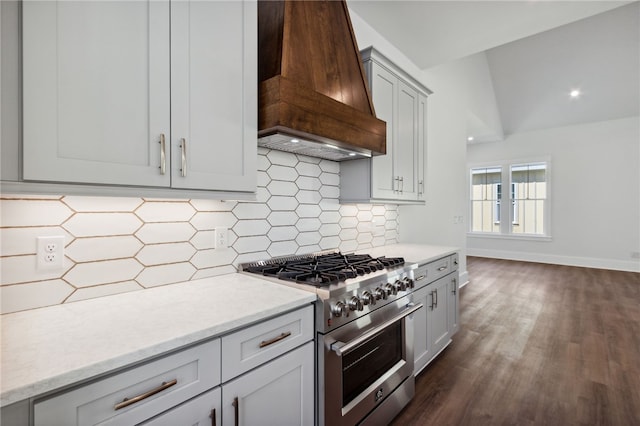 kitchen with custom exhaust hood, lofted ceiling, high end stainless steel range, tasteful backsplash, and dark hardwood / wood-style flooring