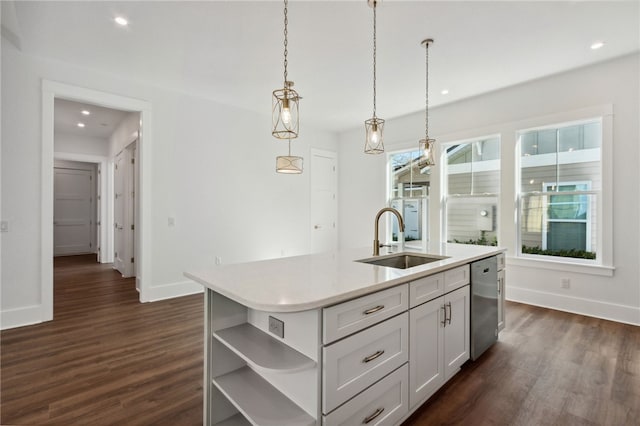 kitchen featuring a kitchen island with sink, sink, stainless steel dishwasher, decorative light fixtures, and dark hardwood / wood-style flooring