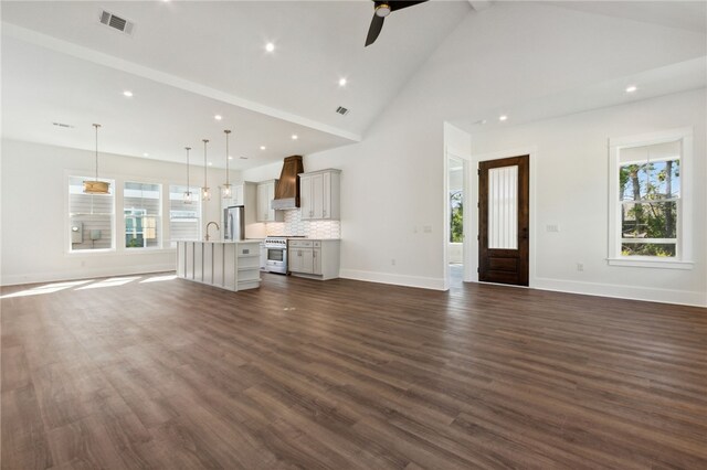 unfurnished living room featuring dark hardwood / wood-style floors, high vaulted ceiling, ceiling fan, and sink