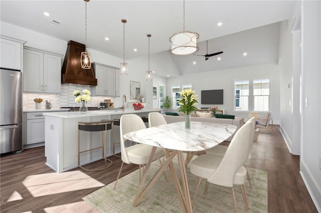 dining area featuring dark hardwood / wood-style flooring, high vaulted ceiling, and sink