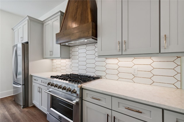 kitchen with custom exhaust hood, dark wood-type flooring, light stone countertops, tasteful backsplash, and stainless steel appliances