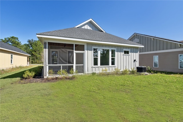 rear view of property featuring a yard, central AC unit, and a sunroom