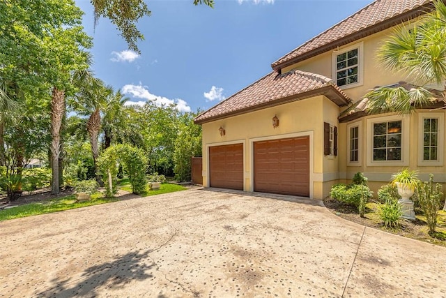 265 Harbor Pointe Dr, Brunswick, GA 31523 - view of property exterior featuring a tile roof, concrete driveway, stucco siding, and an attached garage