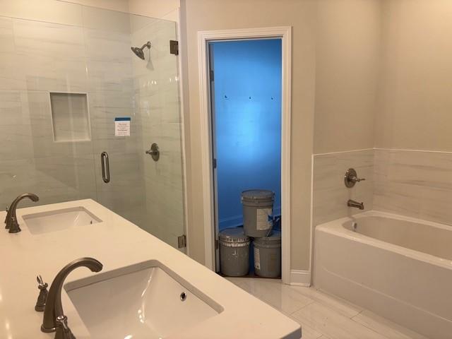 full bathroom featuring a stall shower, a sink, and a bath