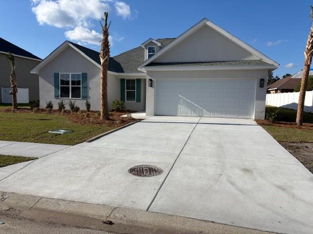 single story home with an attached garage, driveway, a front yard, and stucco siding