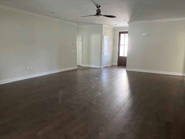 spare room featuring a ceiling fan, crown molding, baseboards, and dark wood-style flooring