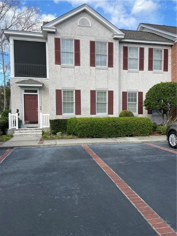 townhome / multi-family property featuring stucco siding, uncovered parking, and a shingled roof