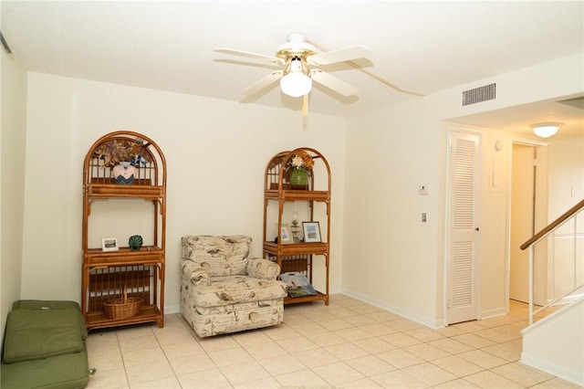 sitting room with stairway, ceiling fan, light tile patterned flooring, and baseboards