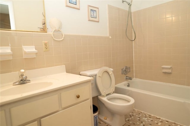full bath with tile walls, toilet, washtub / shower combination, vanity, and tile patterned floors